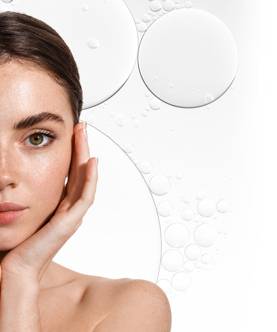 Close-up of a woman touching her face, beside clear serum droplets
